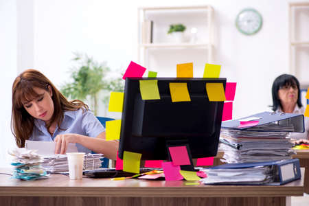 Two female employees and excessive work in the officeの写真素材