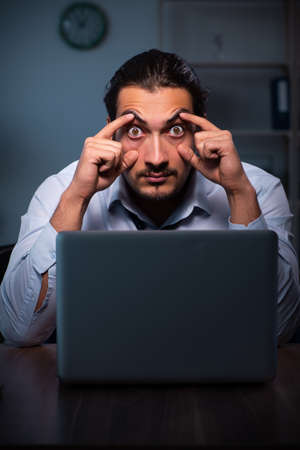 Young male employee working in the office night timeの写真素材