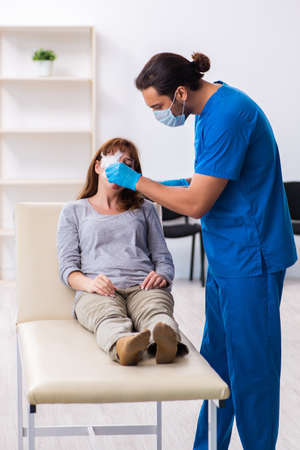 Young head injured woman visiting young male doctorの写真素材