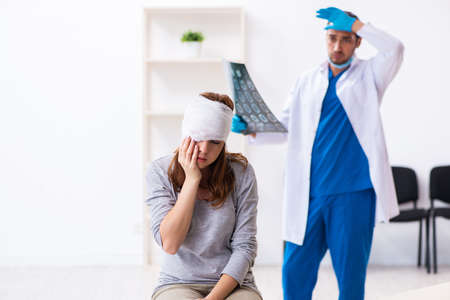 Young head injured woman visiting young male doctorの写真素材