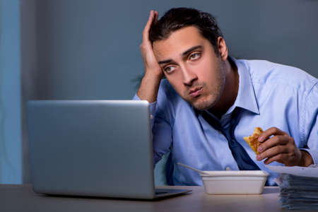 Hungry employee working late in the officeの写真素材