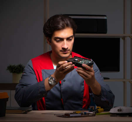 Young handsome repairman repairing computer