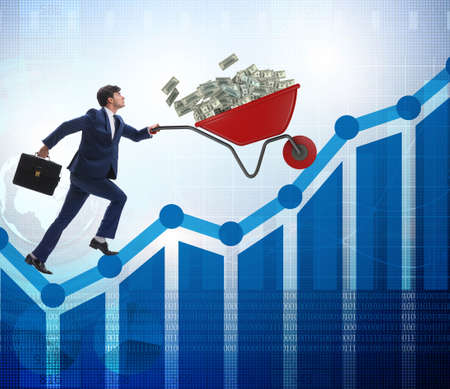 Businessman pushing wheelbarrow full of dollar moneyの写真素材