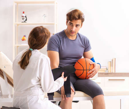 Handsome basketball player visiting female doctor traumatologist