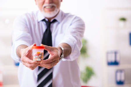 Old sick employee suffering at workplaceの写真素材