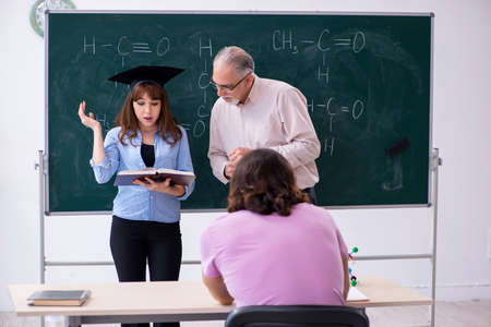 Old chemist teacher and two students in the classroomの写真素材