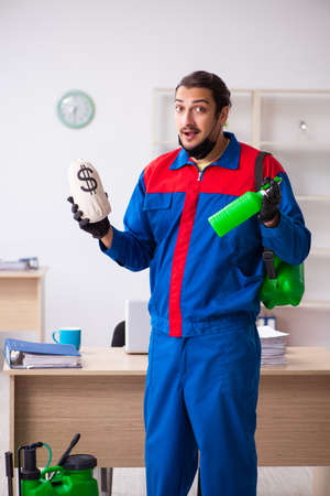 Young male contractor disinfecting officeの写真素材