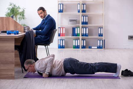 Two employees doing physical exercises at workplaceの写真素材