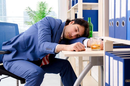 Young businessman employee drinking in the officeの写真素材