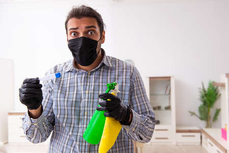 Young male contractor cleaning the house in coronavirus concept