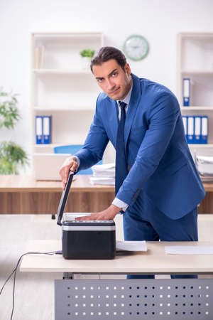 Young male employee making copies at copying machine