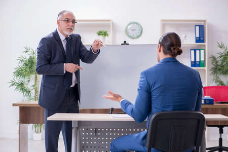 Yound and old employees in business presentation conceptの写真素材