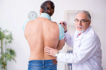 Young back injured man visiting experienced male doctor