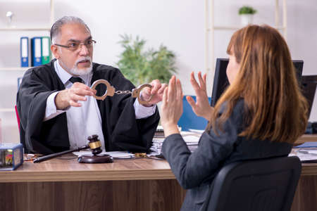 Old male judge and female client in the officeの写真素材