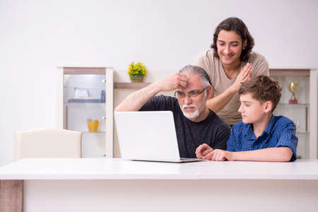 Grandfather learning new technology from son and grandsonの写真素材