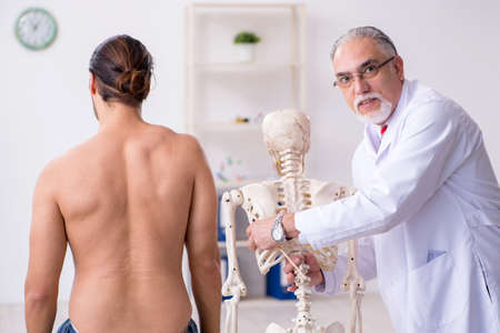 Young back injured man visiting experienced male doctor
