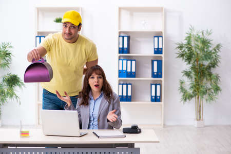 Young male courier delivering cake to the officeの写真素材