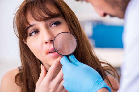 Young woman visiting male doctor dermatologistの写真素材