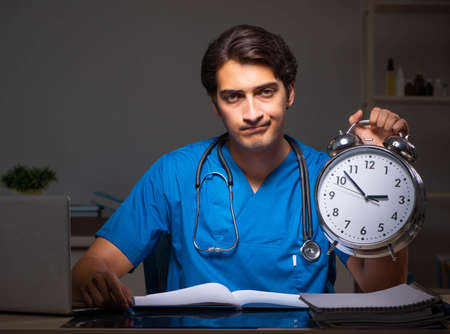Young handsome doctor working night shift in hospitalの写真素材