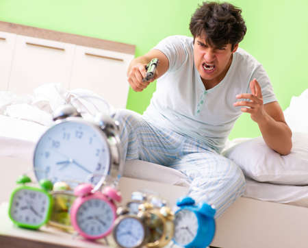 Young man having trouble waking up in early morningの写真素材
