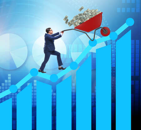 The businessman pushing wheelbarrow full of dollar moneyの写真素材
