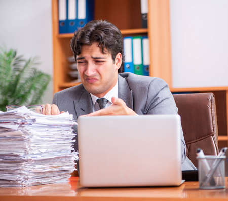 Young handsome businessman unhappy with excessive work