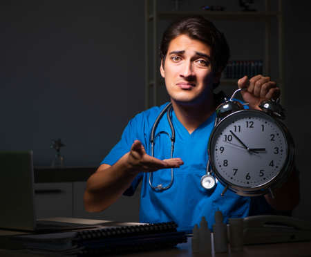 Young handsome doctor working night shift in hospitalの写真素材