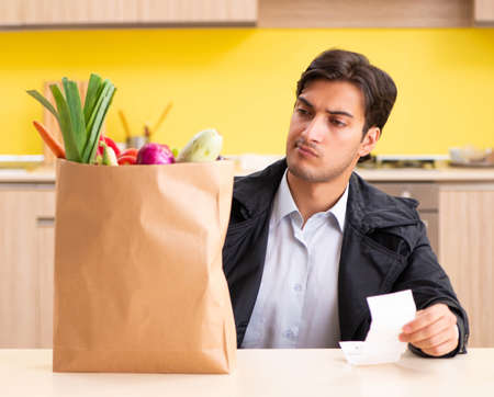 Young handsome man with vegetables in kitchenの写真素材
