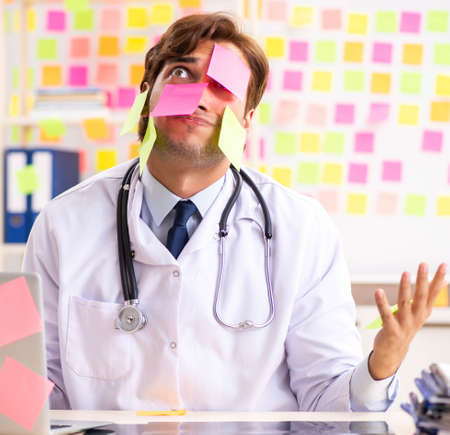 Male doctor with many conflicting priorititesの写真素材