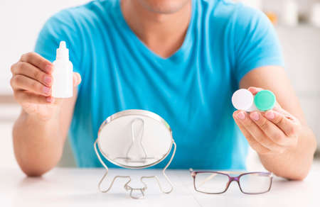 The man trying contact lenses at home
