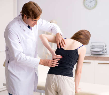 Female patient visiting young handsome doctor chiropractorの写真素材