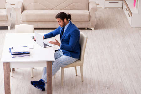 Young male employee working from house in self-isolation conceptの写真素材