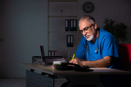 Aged male doctor in the hospital at nightの写真素材
