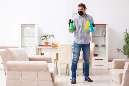 Young male contractor cleaning the house in coronavirus conceptの写真素材