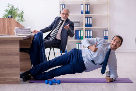 Two employees doing physical exercises at workplaceの写真素材