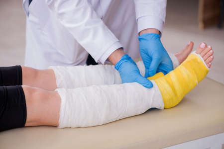Young leg injured woman visiting old doctor traumatologist