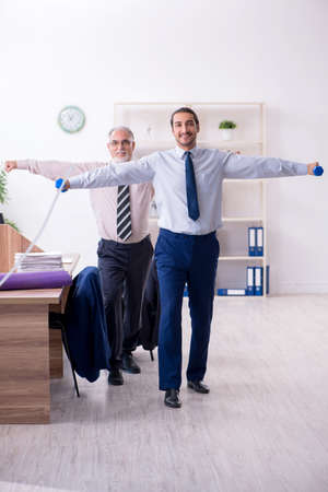 Two employees doing physical exercises at workplaceの写真素材