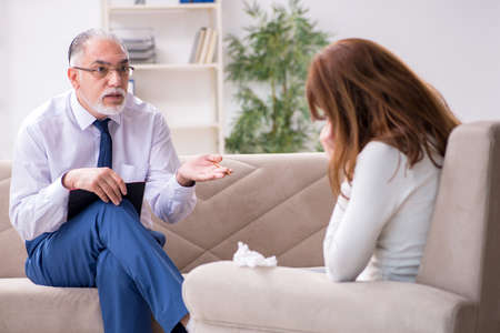 Young woman visiting old male doctor psychologistの写真素材