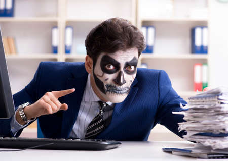 Businessmsn with scary face mask working in officeの写真素材