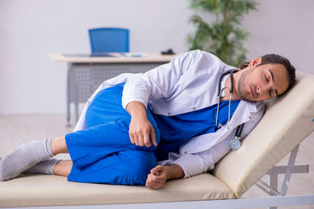 Young male doctor being tired after night shiftの写真素材