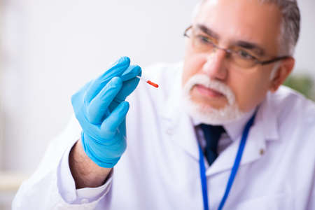 Old male expert criminologist working in the lab for evidence