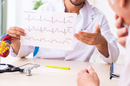 Old man visiting young male doctor cardiologistの写真素材