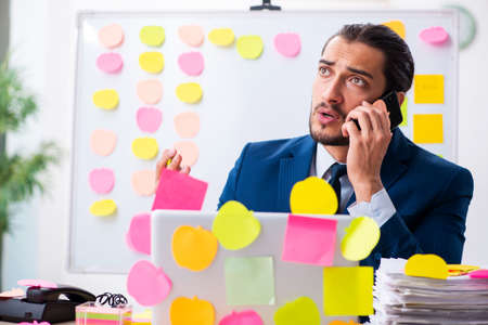 Young male employee in conflicting priorities conceptの写真素材