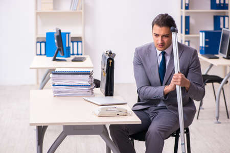 Leg injured employee in the officeの写真素材