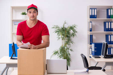 Young male courier delivering postbox to the officeの写真素材