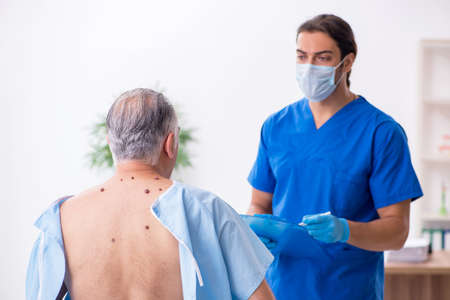 Old man visiting young male doctor dermatologistの写真素材