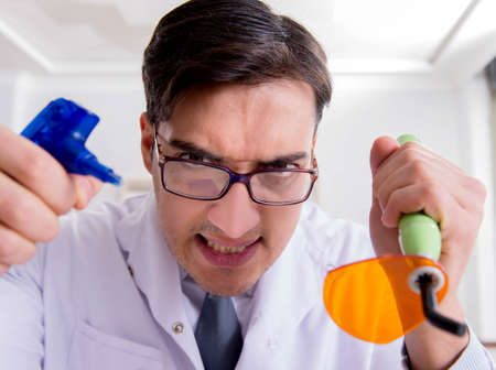Funny dentist with curing light in medical concept
