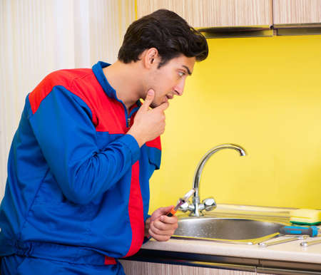 Plumber repairing tap at kitchenの写真素材