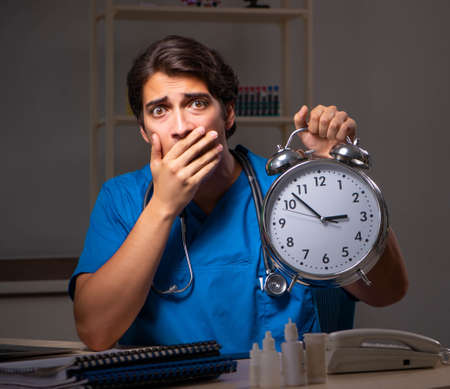 Young handsome doctor working night shift in hospitalの写真素材
