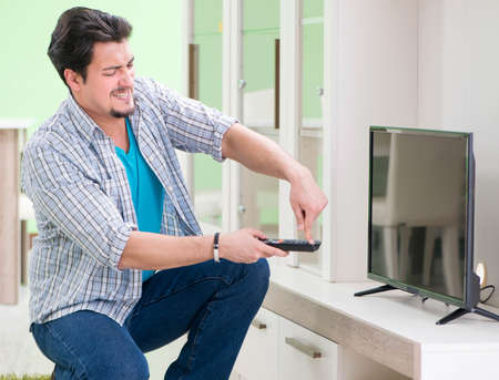 Young man husband repairing tv at homeの写真素材